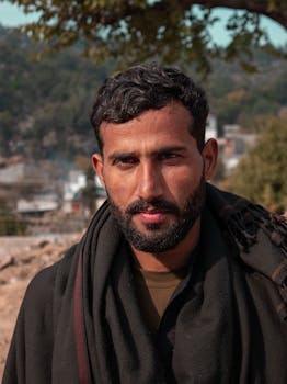Close-up portrait of a South Asian man outdoors in Mansehra, Pakistan, with a calm expression.